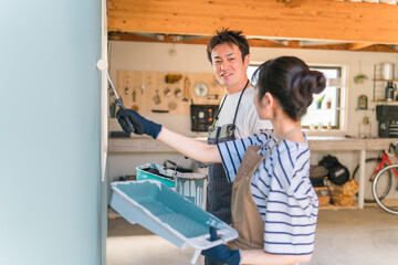 壁の塗装をする日本人の男女の後ろ姿（DIY・リノベーション・リフォーム）
