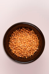 Red lentil in bowl isolated on pink background. Top view