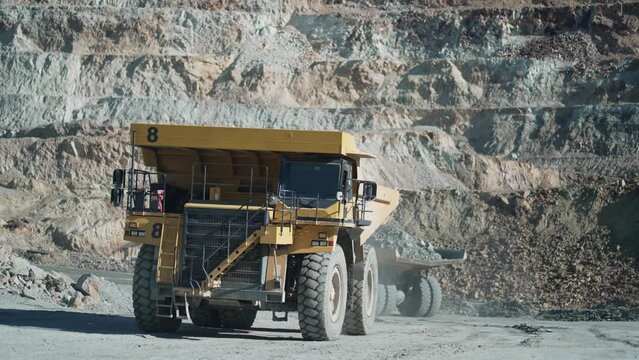 Heavy mining dump trucks driving along the opencast open mine pit, slow motion