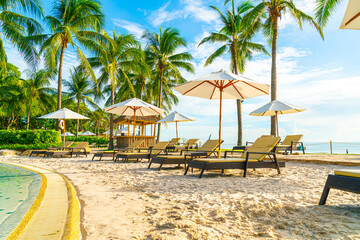 Beautiful luxury umbrella and chair around outdoor swimming pool in hotel and resort with coconut palm tree on sunset  or sunrise sky