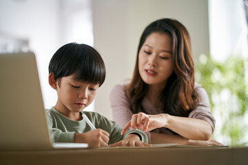 young asian mother helping son with homework at home - obrazy, fototapety, plakaty