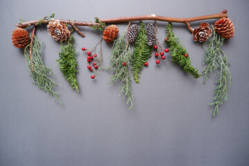 Winter green, berries and acorn decoration on gray background. Winter holiday composition. Christmas decoration. Christmas garland.