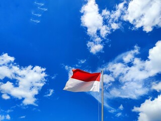The Indonesian flag flutters in the wind under the blue sky