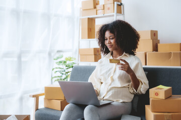 Woman using laptop computer and credit card for online shopping at home. Female happily utilizes her laptop and credit card for convenient online purchases.