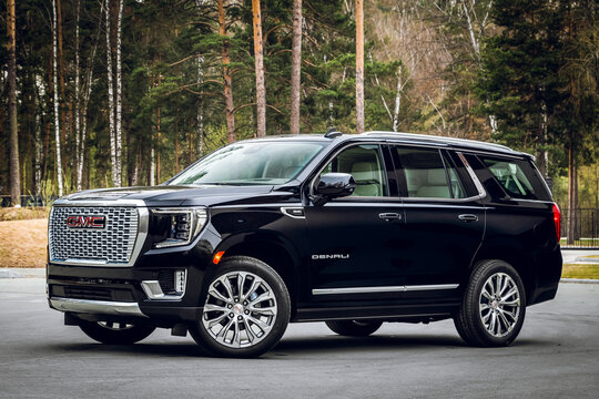  Novosibirsk, Russia - April  25, 2023: black GMC Yukon Denali  parked on the street on a warm summer day against the backdrop of  park