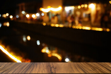 Empty dark wooden table in front of abstract blurred boken bankground of restaurant.