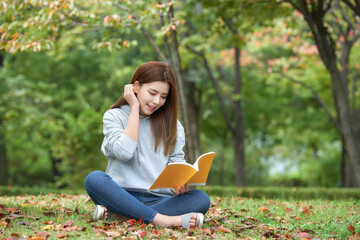 A beautiful woman, a college student, reading in a forest park