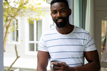Portrait of happy african american man holding cup of coffee at home