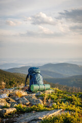 Hiking backpack with mat on rock during trek in mountains. Camping and travel equipment for...