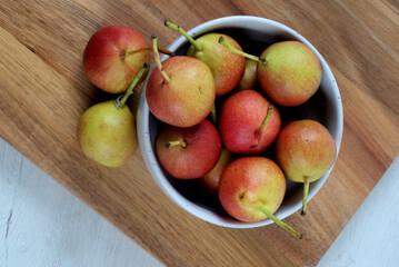 White bowl with small pears on wooden board