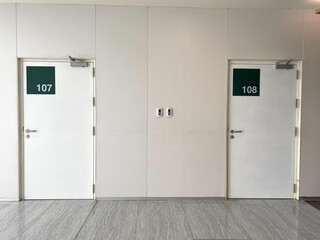 2 white doors in the building and the numbers 107 and 108 on the green sign on the doors. examination room in the hospital ,doctor's room in the hospital