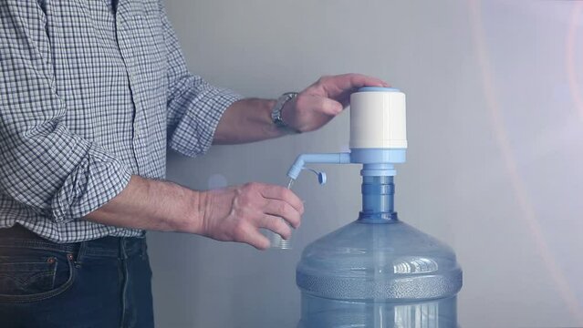 A man drinks imported bottled drinking water. A flask with artesian clean water in the office, at work.