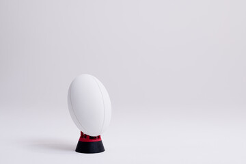 White rugby ball on red and black stand with copy space on white background