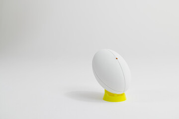 White rugby ball on yellow stand with copy space on white background