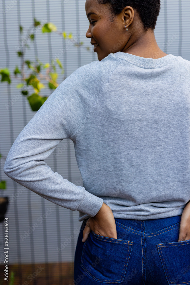 Canvas Prints Rear view of happy african american woman wearing grey sweatshirt against white fence