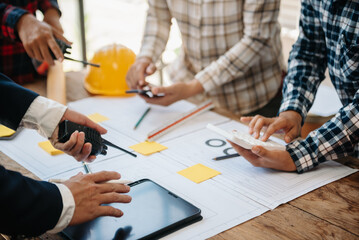 Engineer teams meeting working together wear worker helmets hardhat on construction site in modern city.