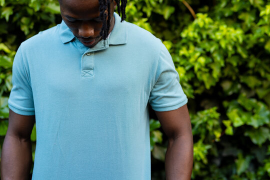 Midsection of african american man wearing pale blue polo shirt in garden - Powered by Adobe