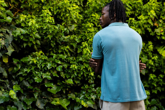 Rear view of african american man with dreadlocks wearing pale blue polo shirt in garden, copy space