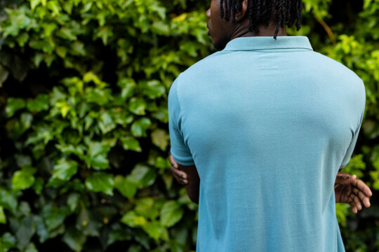 Rear view of african american man with dreadlocks wearing pale blue polo shirt in garden, copy space