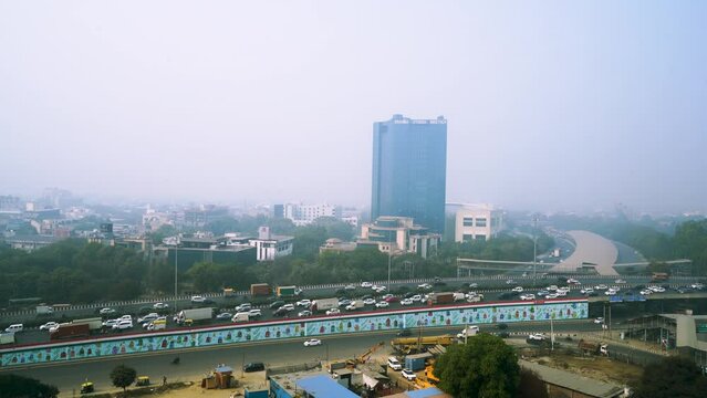 gurgaon cityscape with traffic cars bikes on elevated road crossing over with skyscrapers in the background showing the congestion and crowd of the city