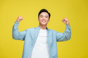 Cheerful excited man standing isolated over yellow background, celebrating success