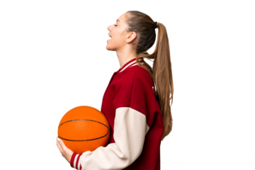 Young blonde woman playing basketball over isolated chroma key background laughing in lateral position