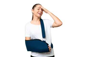 Young blonde woman with broken arm and wearing a sling over isolated chroma key background smiling...