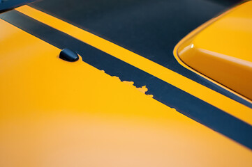 Black destroyed tattered fast stripes on the hood of a sports car. Detail of a peeling sticker on a...