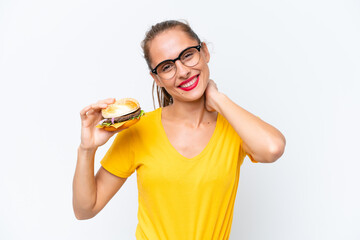Young caucasian woman holding a burger isolated on white background laughing