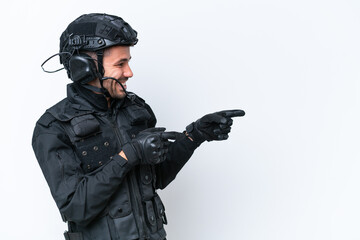 Young caucasian SWAT man isolated on white background pointing finger to the side and presenting a product