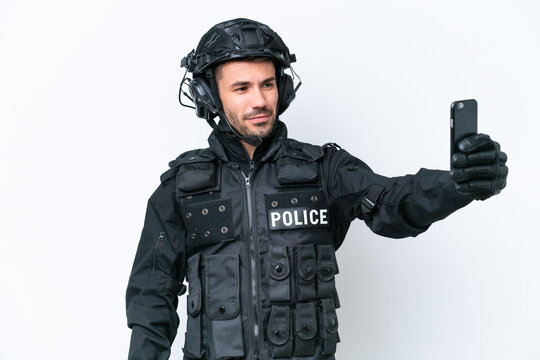 Young caucasian SWAT man isolated on white background making a selfie