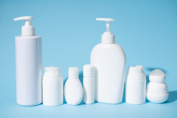 Still life with a set of white mockup bottles with cosmetic products, isolated blue pastel background