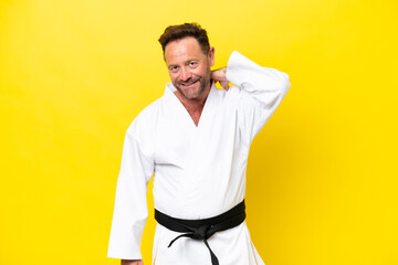 Middle age caucasian man doing karate isolated on yellow background laughing