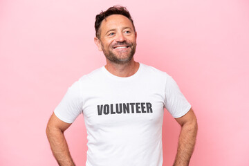 Obraz premium Middle age volunteer man isolated on pink background isolated on pink background posing with arms at hip and smiling