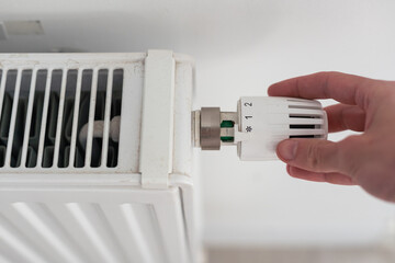 Building thermoregulation. The man turns the radiator knob.