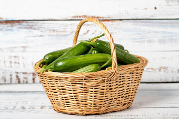 Fresh cucumber in a wicker basket over wooden background. Cucumber harvest season concept. Vegetables for a healthy diet