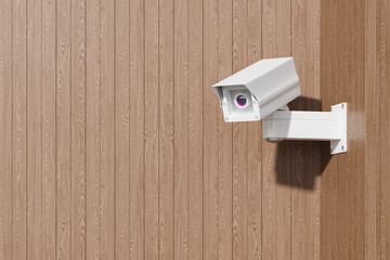 CCTV camera mounted on empty wooden wall, outdoors video control