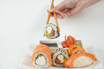 Sushi roll holding in eating sticks. Japanese traditional Cuisine