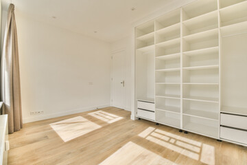 an empty room with wooden floor and white bookcases on the wall, there is sunlight shining through the window