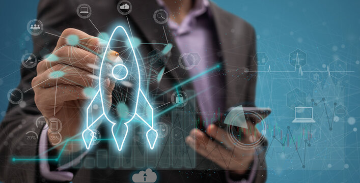 Startup concept with businessman holding tablet or smartphone transparent rocket in launching with network connection on modern virtual interface.StartUp Programming Team.Website designer working.