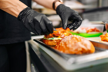 chef hand cooking cheeseburger with vegetables and meat on restaurant kitchen