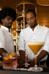 Fototapeta na wymiar vertical photo of two latin bartenders with two cocktails