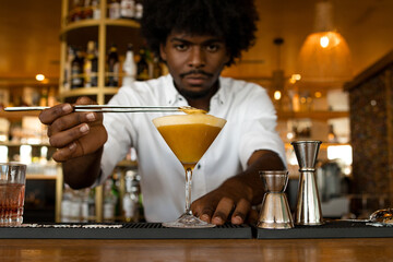 latin bartender with curly hair preparing cocktails