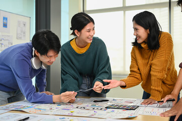 Happy smiling young designers brainstorming and discussing new app features at co working space...