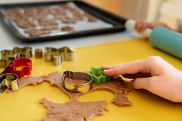 Naklejka na ściany i meble Selective focus. Kids making gingerbread cookies with various Christmas cookie cutters. Gingerbread dough. Family Christmas moments