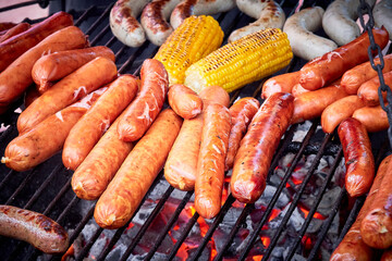 Juicy sausages are fried on coals on a grill in a barbecue