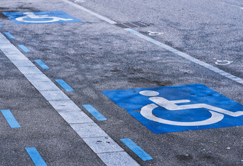 Disabled parking sign painted on the asphalt of a parking lot.