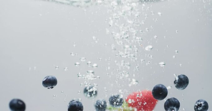 Video of berries falling into water with copy space on white background
