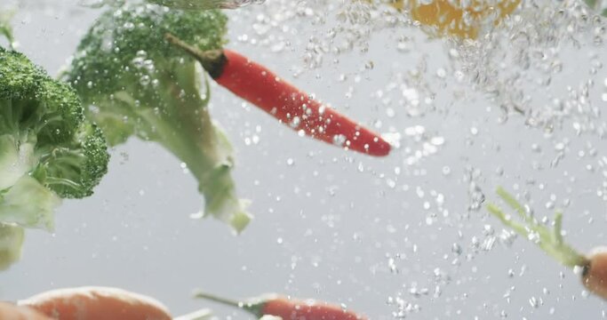 Video of vegetables falling into water with copy space on white background