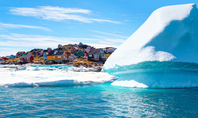 Panoramic view of colorful Kulusuk village in East Greenland - Kulusuk, Greenland - Melting of a iceberg and pouring water into the sea © muratart